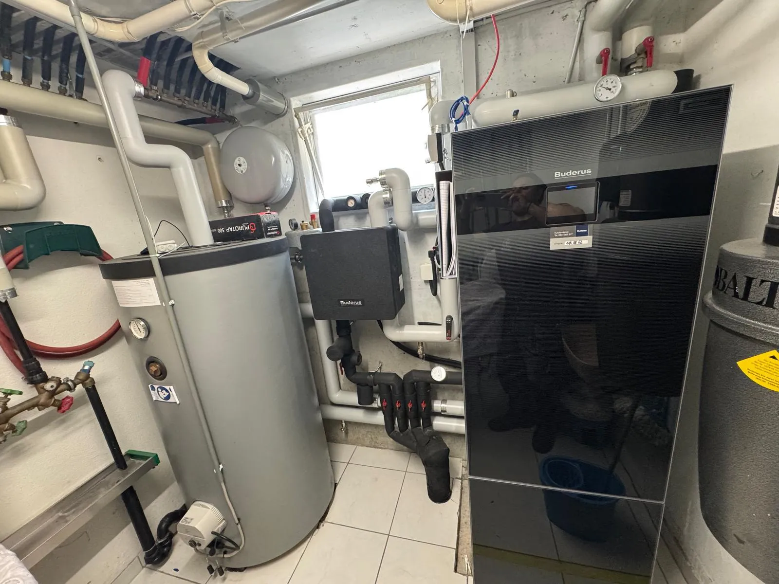 Wärmepumpe mit Warmwasserspeicher im Heizungsraum eines Einfamilienhauses